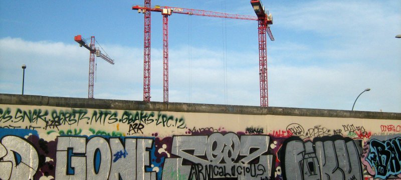 Baukräne an einem Rest der Berliner Mauer