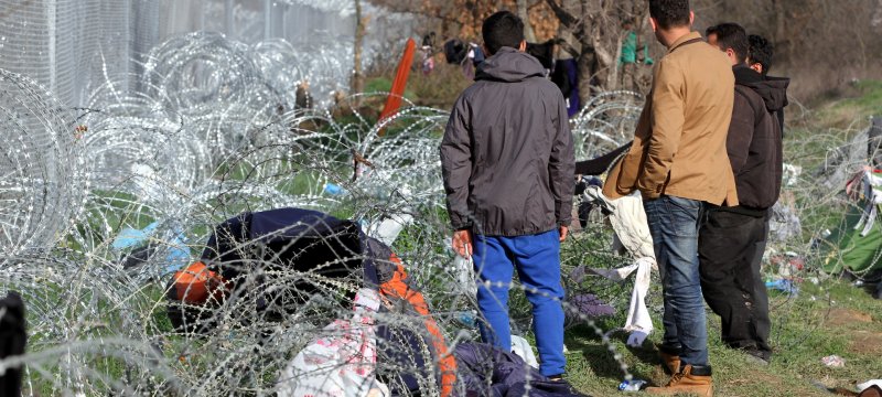 Flüchtlinge auf der Balkanroute vor einem Grenzzaun